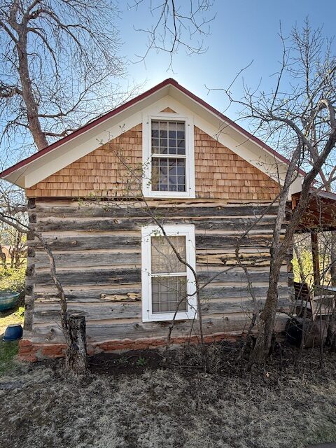 Historic log and shingle building surrounded by dry brush