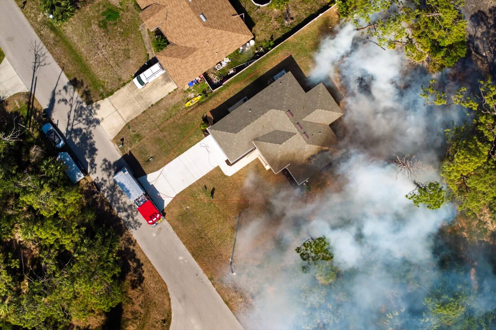 Aerial view of smoke from a vegetation fire burning beside a house